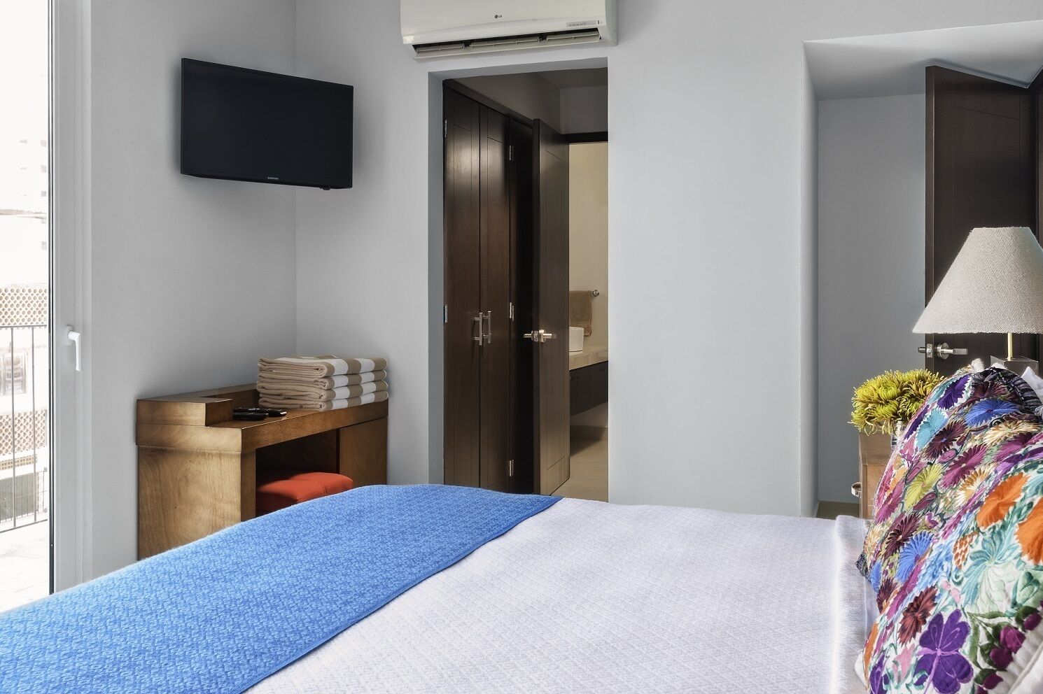 Une chambre d’hôtel comprenant un lit, un bureau avec une chaise, un téléviseur fixé au mur et une porte donnant accès à une salle de bain.
