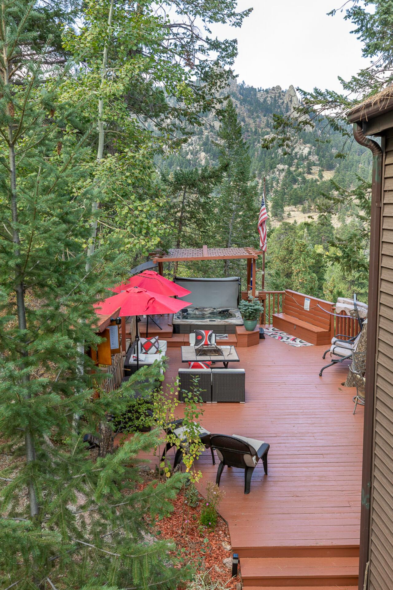 Una terraza de madera con mobiliario exterior, que incluye una mesa, sillas y un banco.