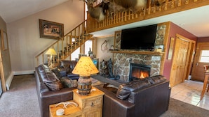 A cozy living room with a fireplace, leather sofa, and a television mounted on the wall. - Rejuvenation Mountian, Estes Park CO (Estes Park)