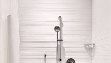 A modern shower with a handheld showerhead, a wall-mounted faucet, and a handheld shower attachment.