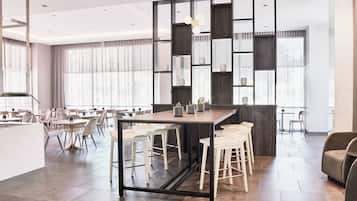 Un comedor moderno con barra central, techos altos y ventanas amplias.