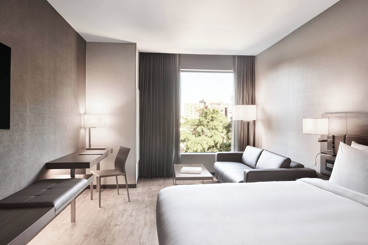 Una habitación de hotel moderna con una cama grande, un escritorio, una silla y un sofá.
