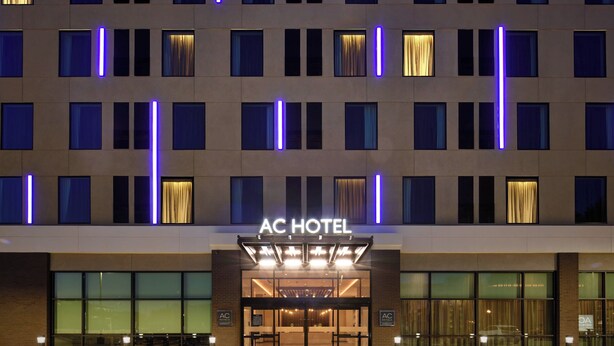 A hotel entrance with a modern facade, illuminated windows, and a prominent AC HOTEL sign. - AC Hotel by Marriott Columbus Downtown (Columbus)