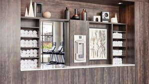A reception area with a wooden reception desk, shelves with towels, a coffee machine, and a mirror. - AC Hotel by Marriott Columbus Downtown (Columbus)