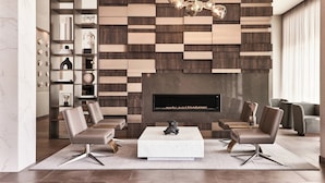 A modern living room with a fireplace, two leather sofas, a coffee table, and a decorative wall panel. - AC Hotel by Marriott Columbus Downtown (Columbus)