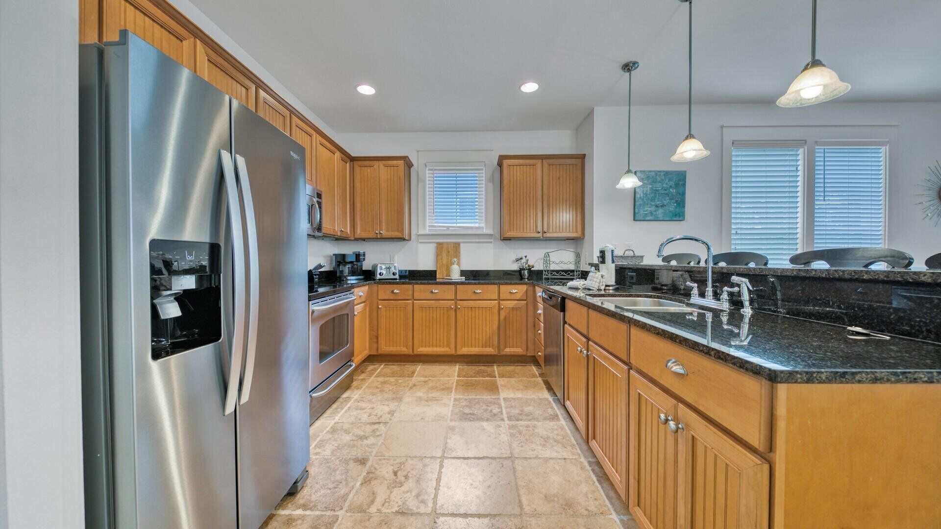 A modern kitchen with wooden cabinets, stainless steel appliances, and a granite countertop.