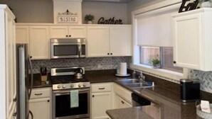 Una cocina moderna con armarios blancos, electrodomésticos de acero inoxidable y encimera de granito.