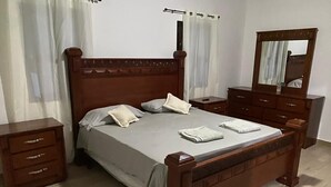 Una camera da letto con un letto di legno, due comodini, una cassettiera e uno specchio.