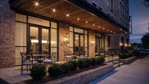 A brick building with a covered patio area featuring outdoor seating and a staircase. - Courtyard by Marriott Thomasville Downtown (Thomasville)