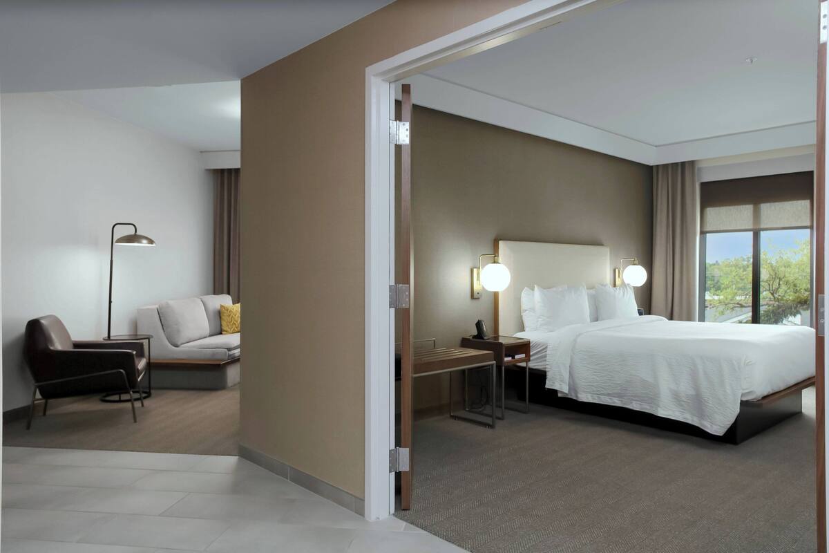 Una habitación de hotel con cama, escritorio, silla y lámpara.