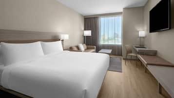 Una habitación de hotel con una cama grande, un escritorio, una silla y un televisor montado en la pared.