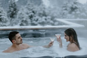 A couple in a hot tub with a snowy landscape in the background. - Alyeska Views - 4 bdr. 2.5 bath  (Anchorage)