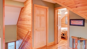 A wooden interior with a sloped ceiling, a wooden door, and a framed sign on the wall. - River Roost - on New River near Boone with fire pit, game room, pet friendly (Todd)