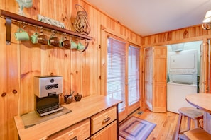 Un intérieur en bois comprenant un coin cuisine équipé d’une machine à café, d’une cuisinière et d’un réfrigérateur.