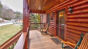 A wooden cabin with a porch, two rocking chairs, and a view of a snowy landscape. - River Roost - on New River near Boone with fire pit, game room, pet friendly (Todd)