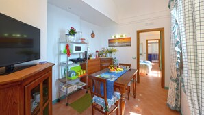A compact living space with a dining area, kitchen, and a TV on a wooden cabinet. - VILLA ROSINELLA WITH SEA VIEW (Amalfi)