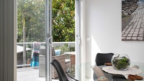 A balcony with wicker furniture, a glass table with a decorative bowl, and a painting on the wall.