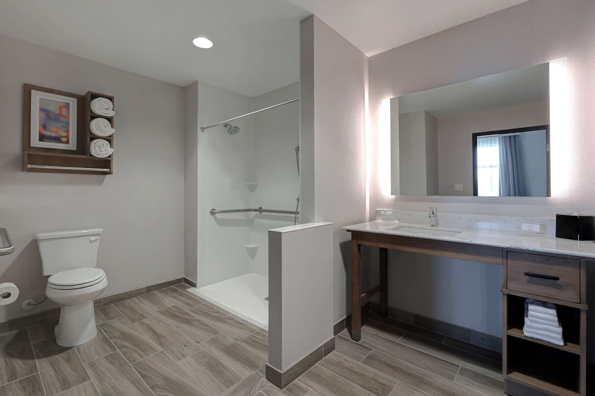 A modern bathroom with a toilet, shower, and vanity.