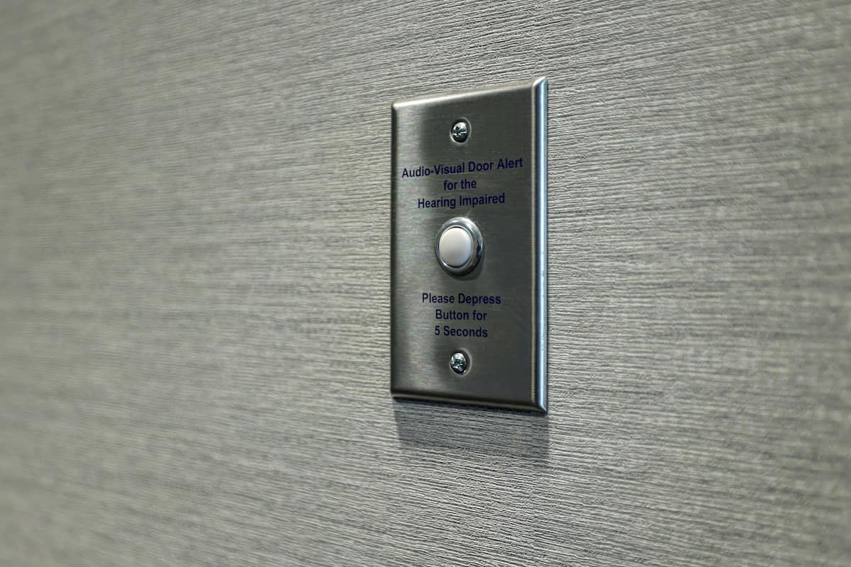 A metallic door with an audio-visual alert system for the hearing impaired, including a depress button to be pressed for 5 seconds.