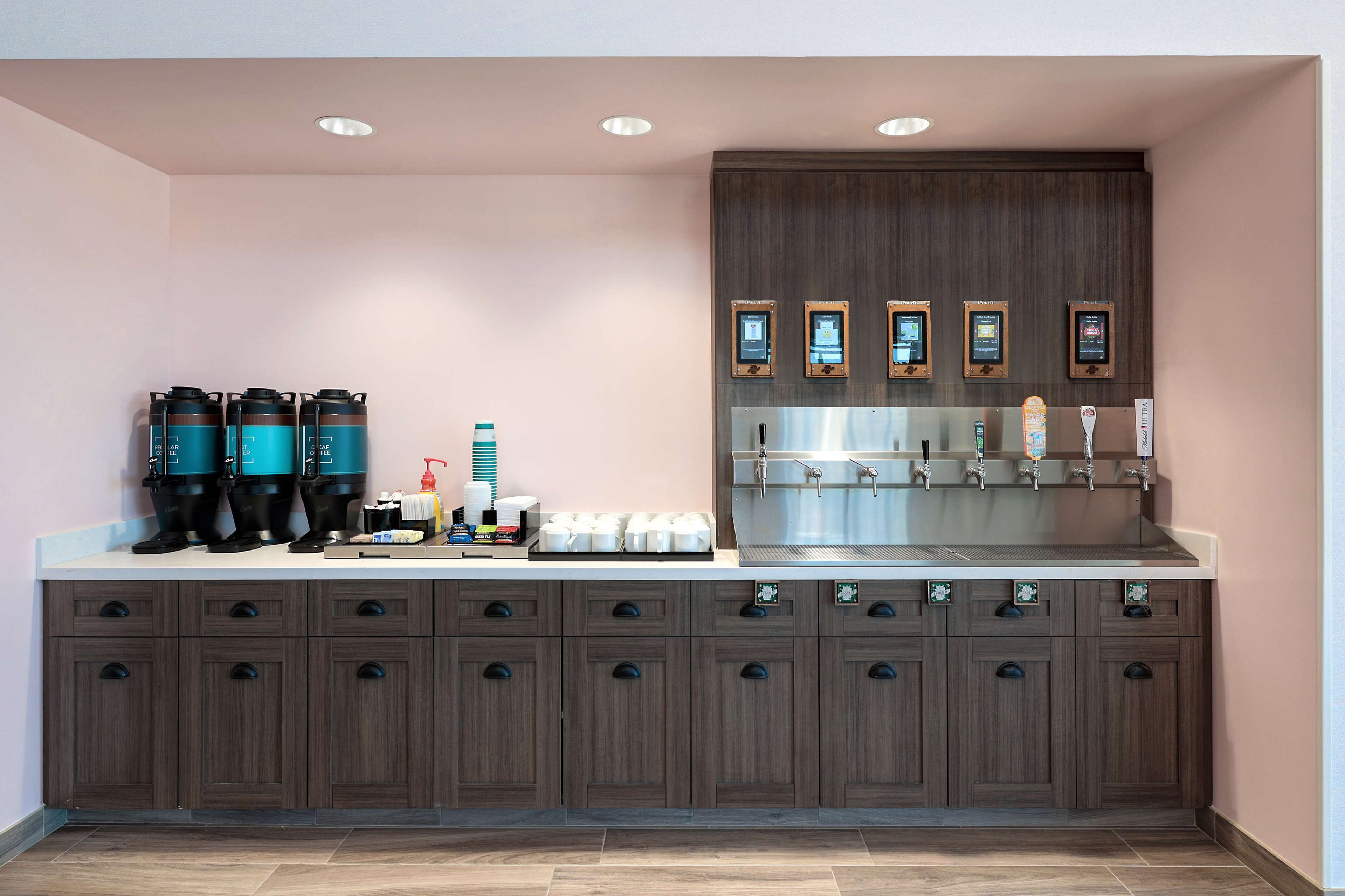 Una cocina moderna con una cafetera espresso integrada, un lavamanos grande y un mueble de madera con varios cajones.