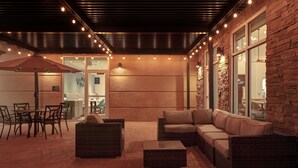 An outdoor patio area with wicker furniture, a table, and chairs.