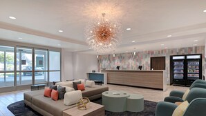 A modern lobby with a reception desk, seating area, and vending machines.