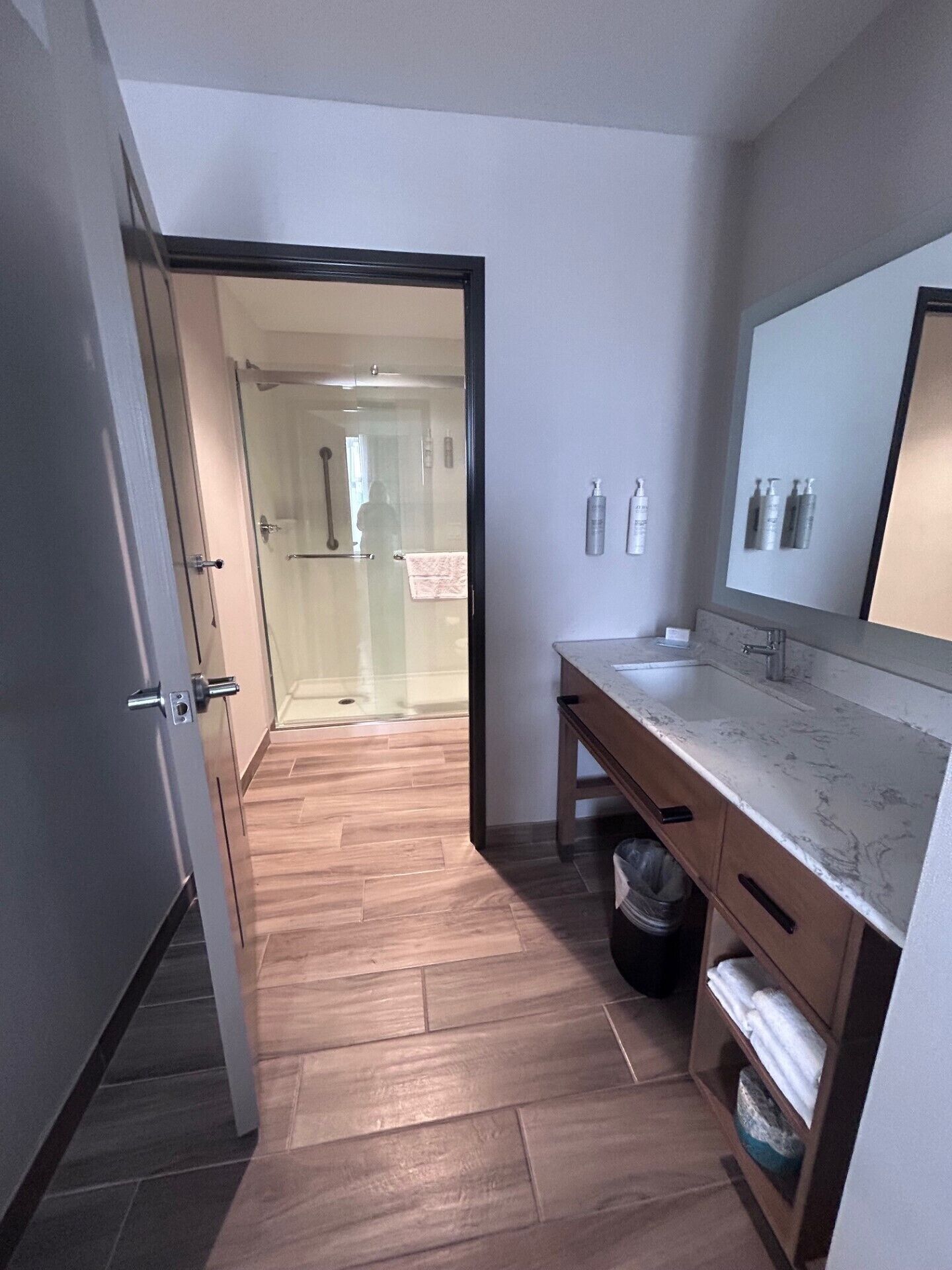 Une salle de bain moderne avec un plancher en bois, un lavabo en marbre et un grand miroir.