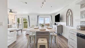 Et moderne køkken med en central ø, barstole, en opvaskemaskine og et fjernsyn.