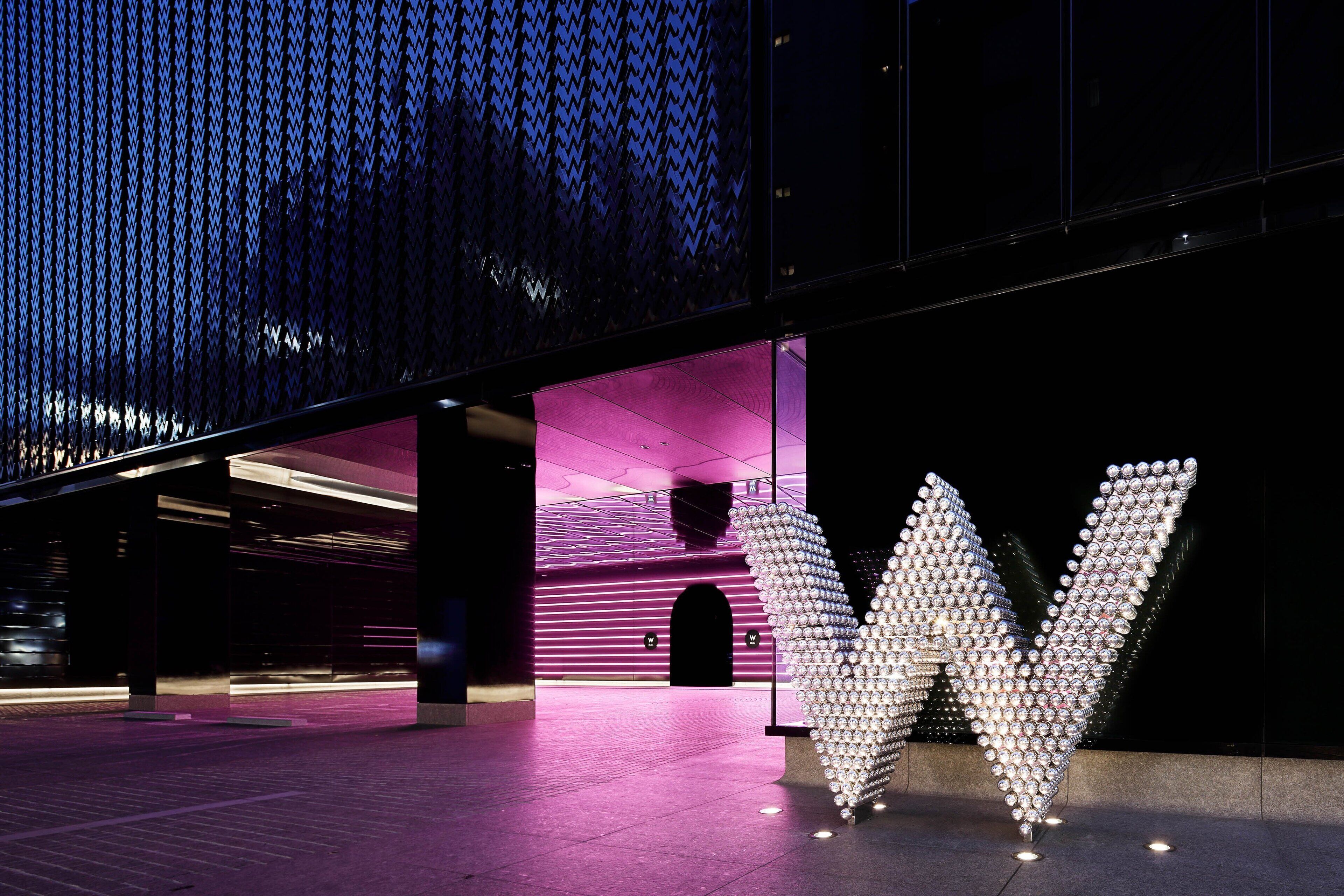 A modern building with a large metallic 'W' sculpture in the foreground.