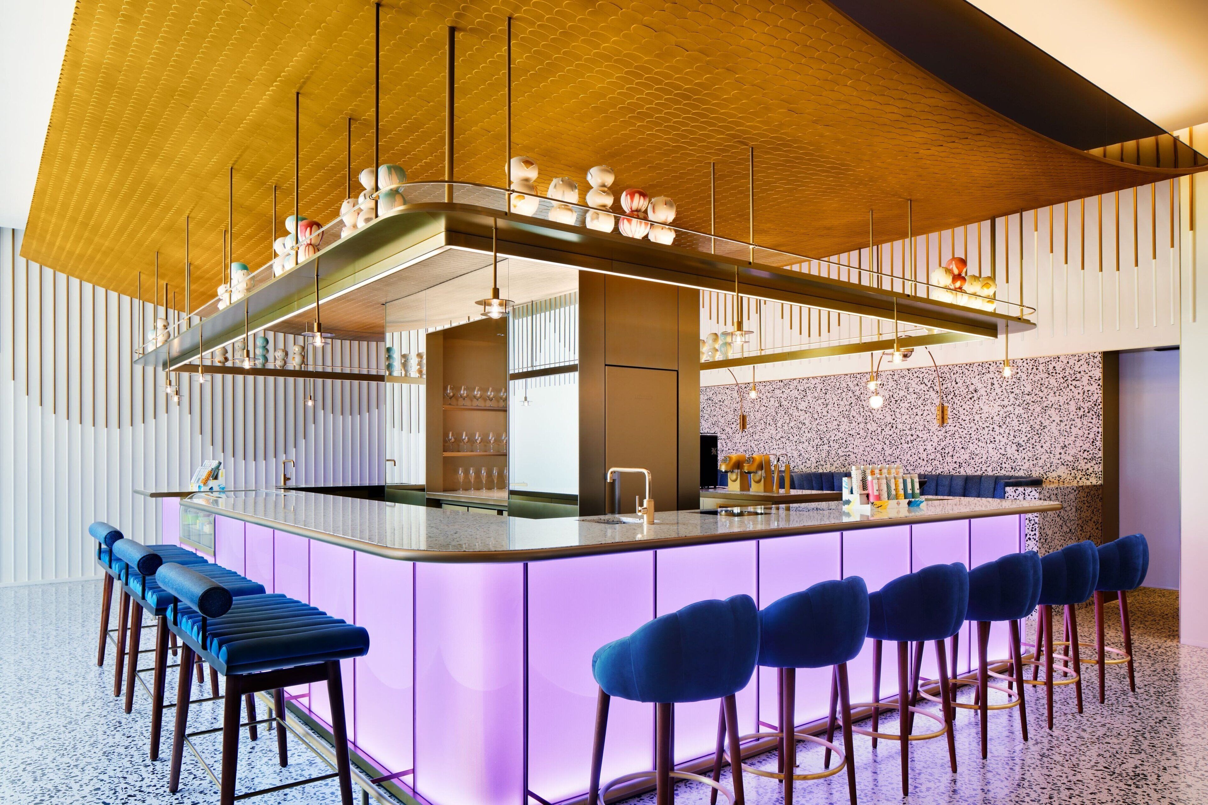 A modern bar area with a central island, bar stools, and pendant lighting.