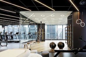 A modern gym with treadmills, exercise balls, and a large window offering a city view.