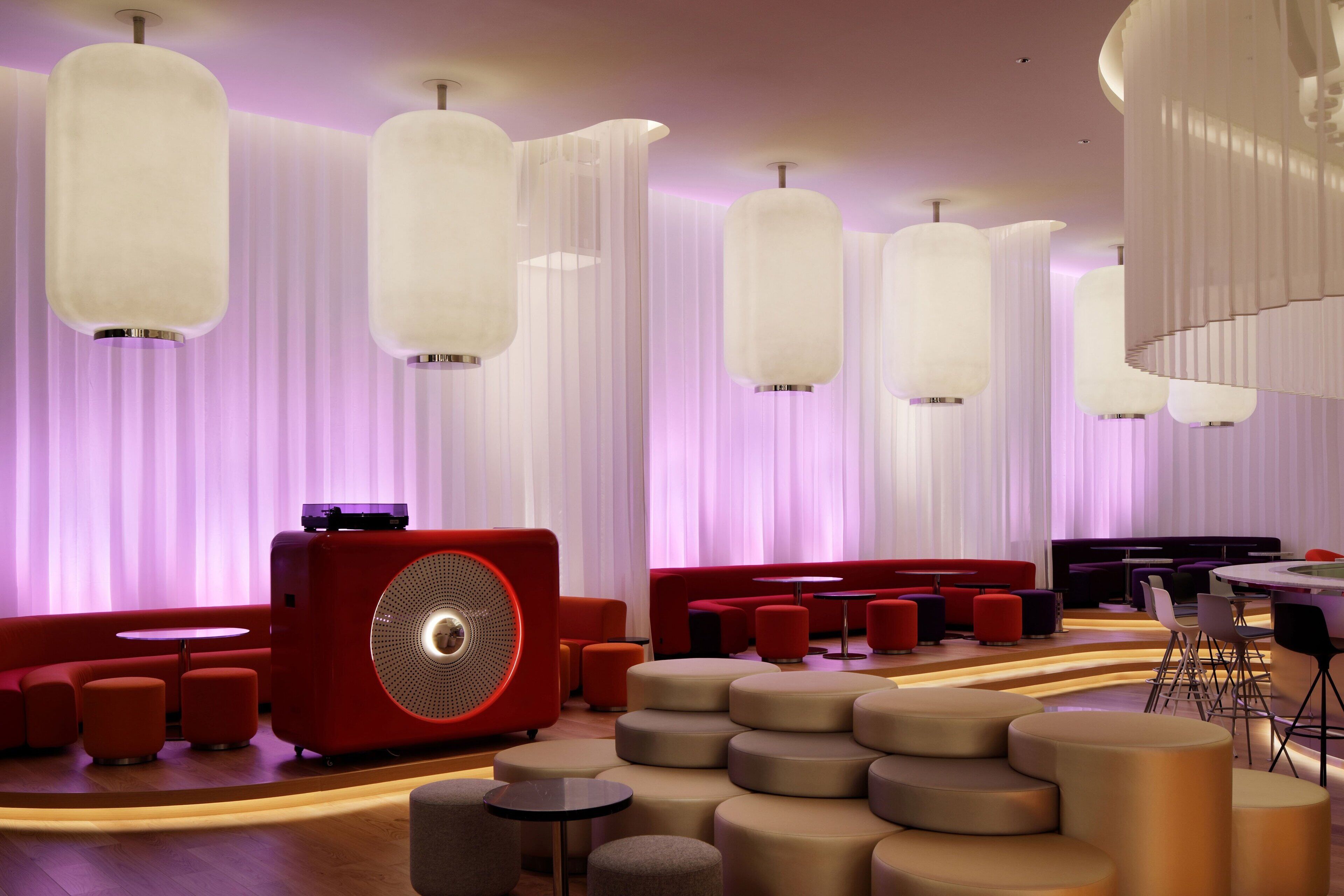 A modern lounge area with tiered seating, a large red speaker, and ambient lighting.