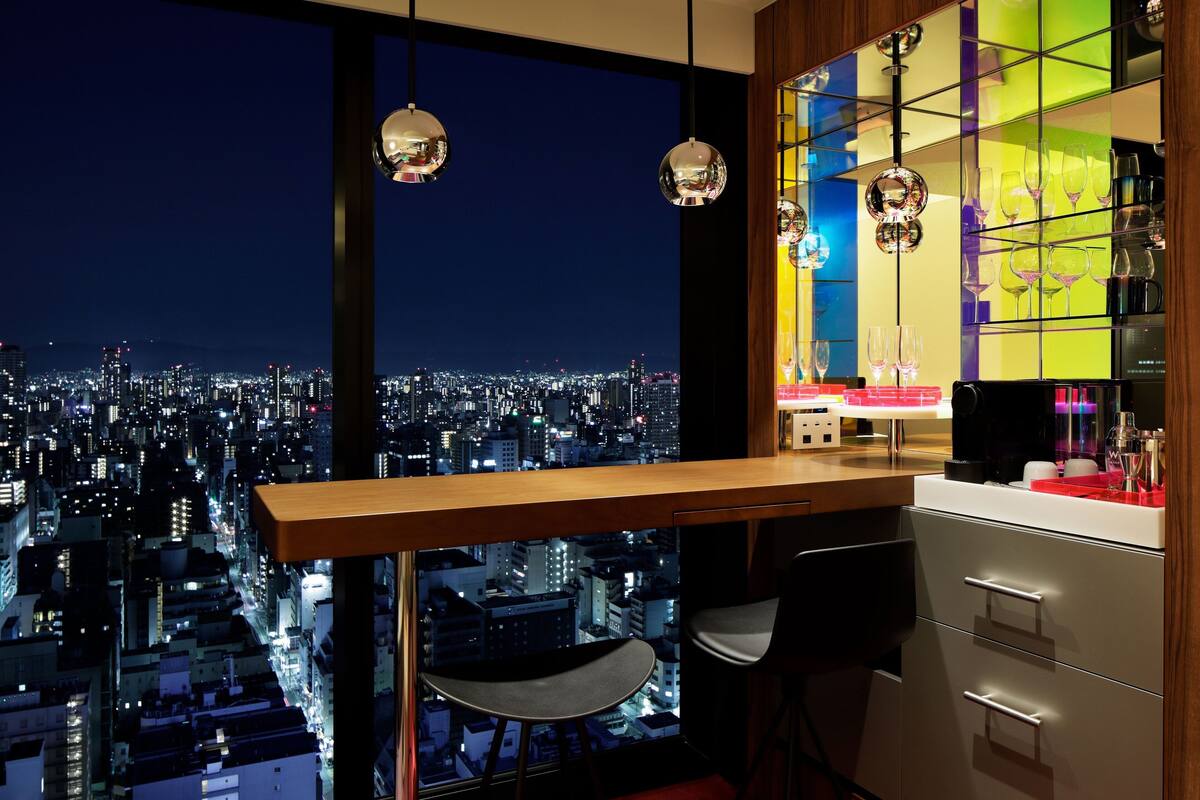 A modern bar area with a city view, a bar counter, and two chairs.