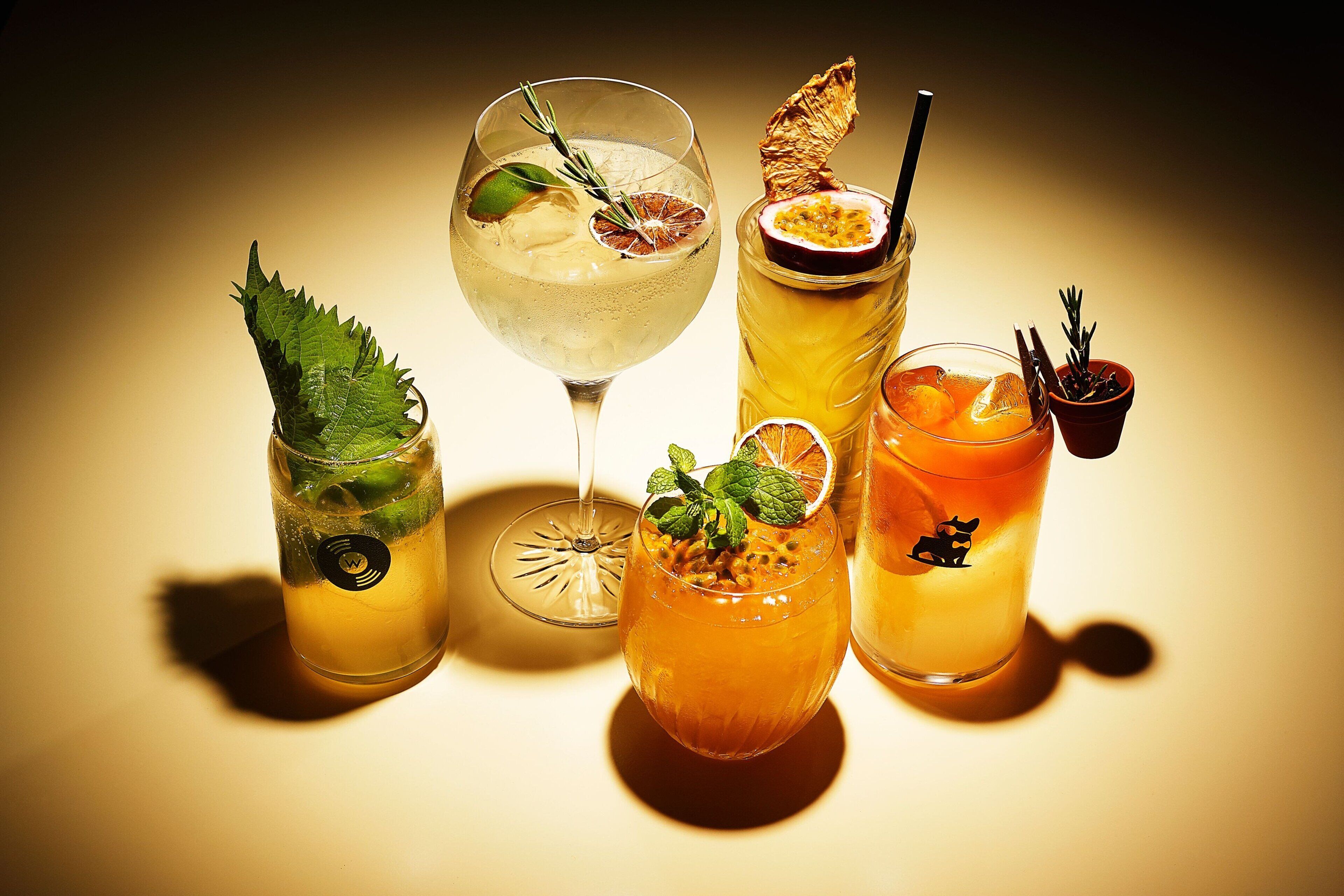 Four different cocktails with garnishes, served in various glassware.