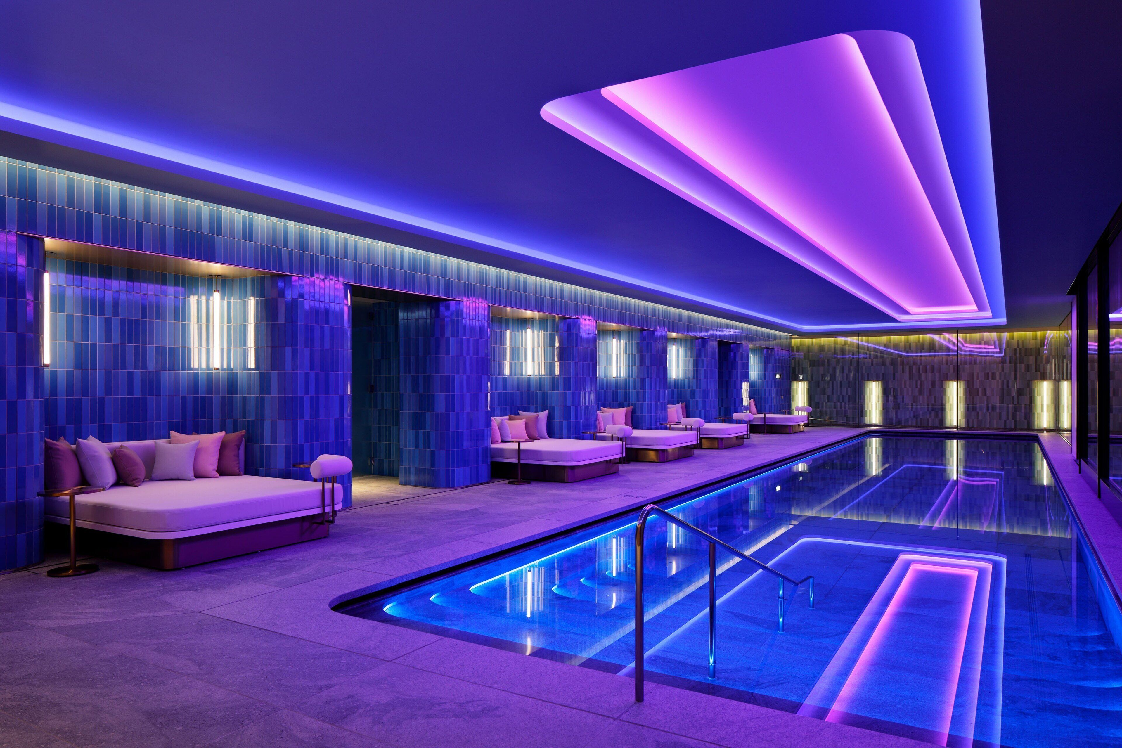 A modern spa with a long pool, multiple seating areas, and ambient lighting.
