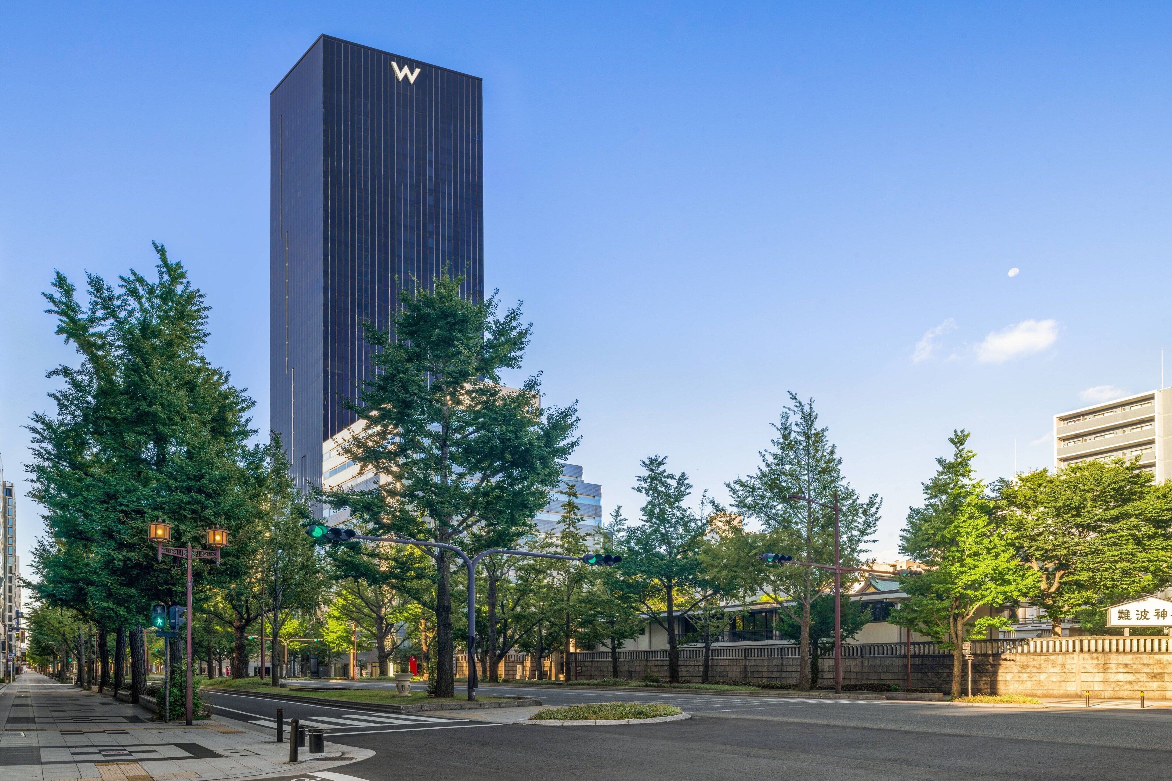 A modern building with a prominent 'W' logo, surrounded by trees and a well-maintained urban street.