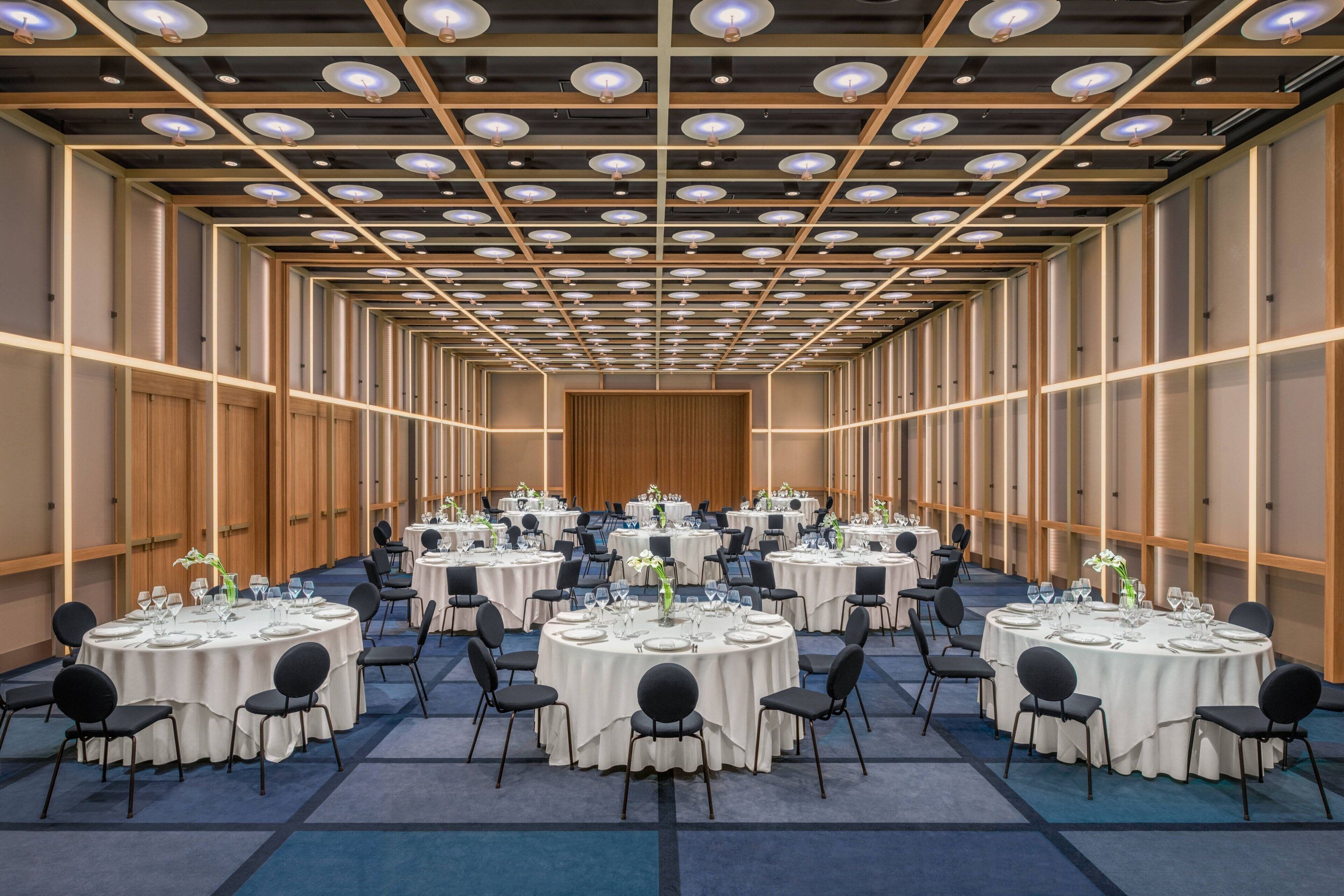 A conference room with multiple round tables, each set with chairs and table settings.