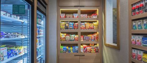 Máquina expendedora de snacks con diversas opciones envaseladas y una sección refrigerada.