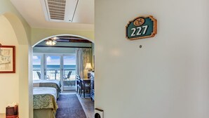 Et hotelværelse med en seng, et skrivebord, en stol og balkonudsigt.