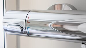 Een close-up van een metallic, reflecterend object met een cirkelvormig ontwerp, mogelijk onderdeel van een modern meubelstuk of apparaat.