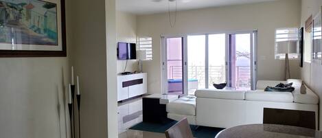 A spacious living room with a white sofa, a dining table, and a ceiling fan.