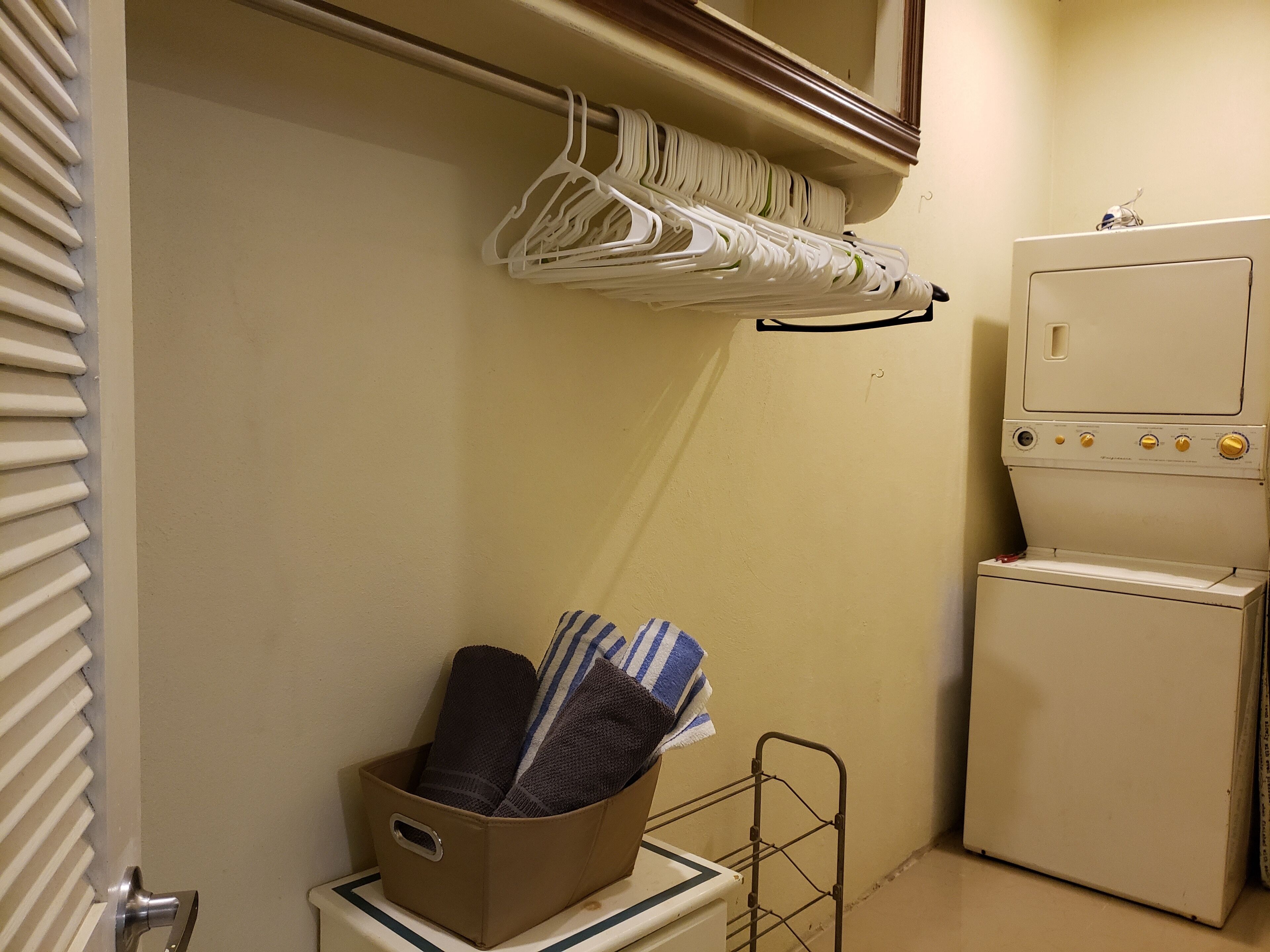A laundry area with a washing machine, a drying rack, and a basket with folded towels.