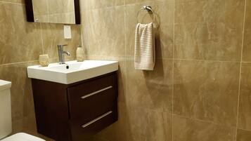 A bathroom with a white sink, dark cabinet, and a towel hanging on a ring.