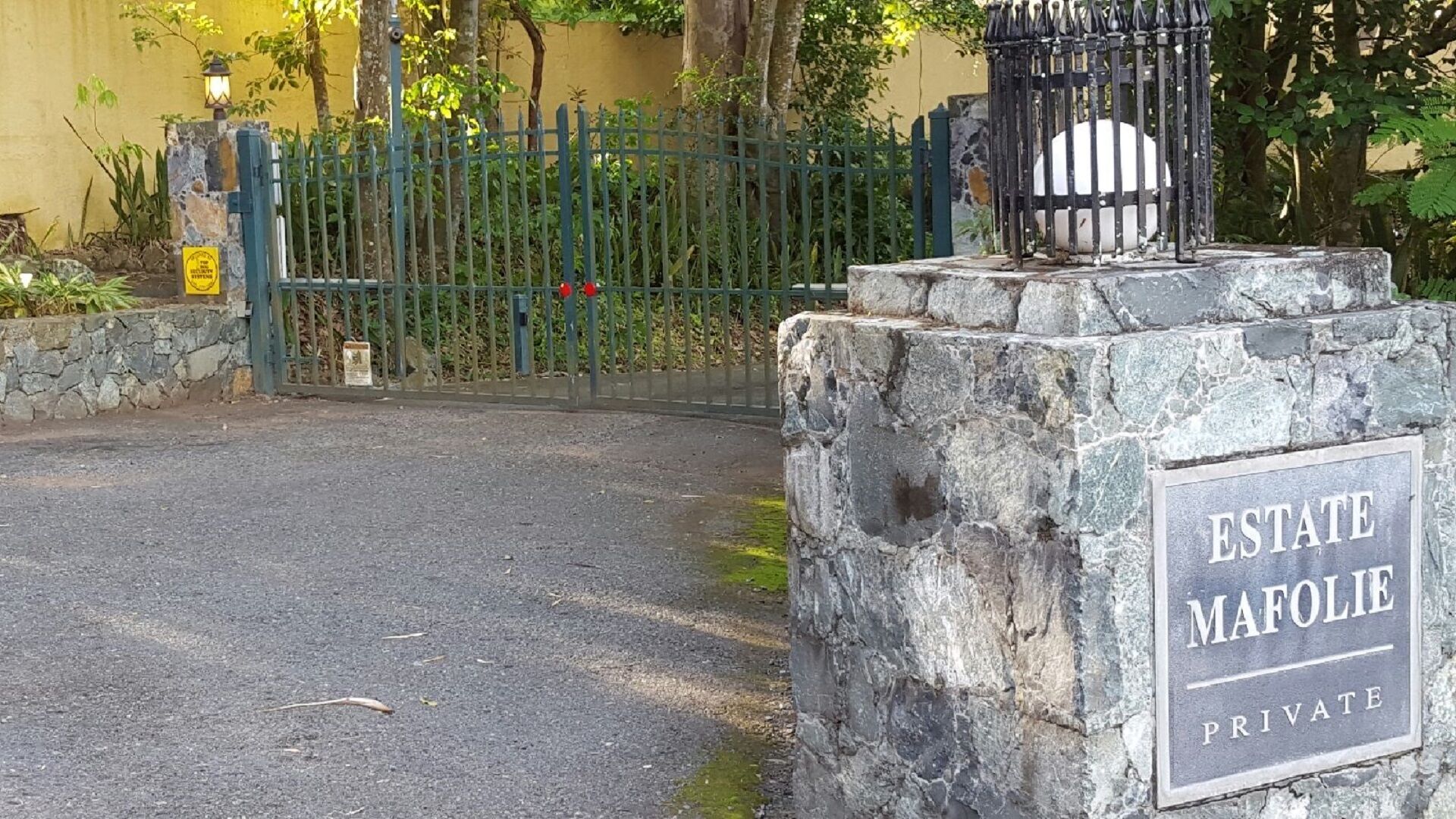 Uma entrada gradeada com uma placa que diz 'ESTATE MAFOLIE PRIVATE'.