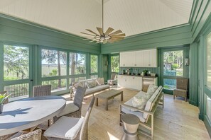 A spacious sunroom with a large dining table, comfortable seating, and a kitchen area.