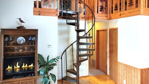 A wooden interior with a spiral staircase, a fireplace, and a mounted bird sculpture.