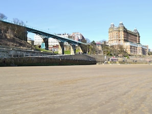 A coastal area with a bridge, a sandy beach, and historic buildings in the background. - Seaton Mote - UK31992 (Staithes)