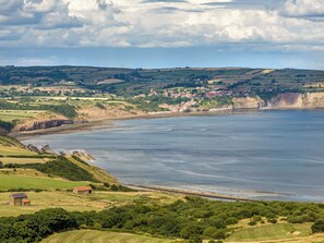 A coastal landscape with a village, green fields, and a large body of water. - Seaton Mote - UK31992 (Staithes)