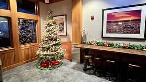 Ein Zimmer mit Weihnachtsbaum, einem gerahmten Bild an der Wand und einer Bar mit Hockern.