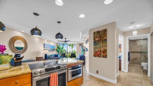 A modern kitchen with granite countertops, stainless steel appliances, and pendant lighting. - Elegant Oceanfront Vistas (Kihei)